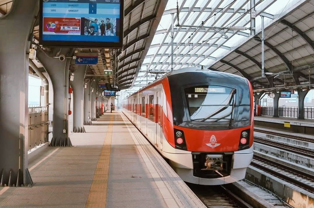 Red Line 列车进站,数字标牌屏幕正显示往 Rangsit 的即时时刻表。